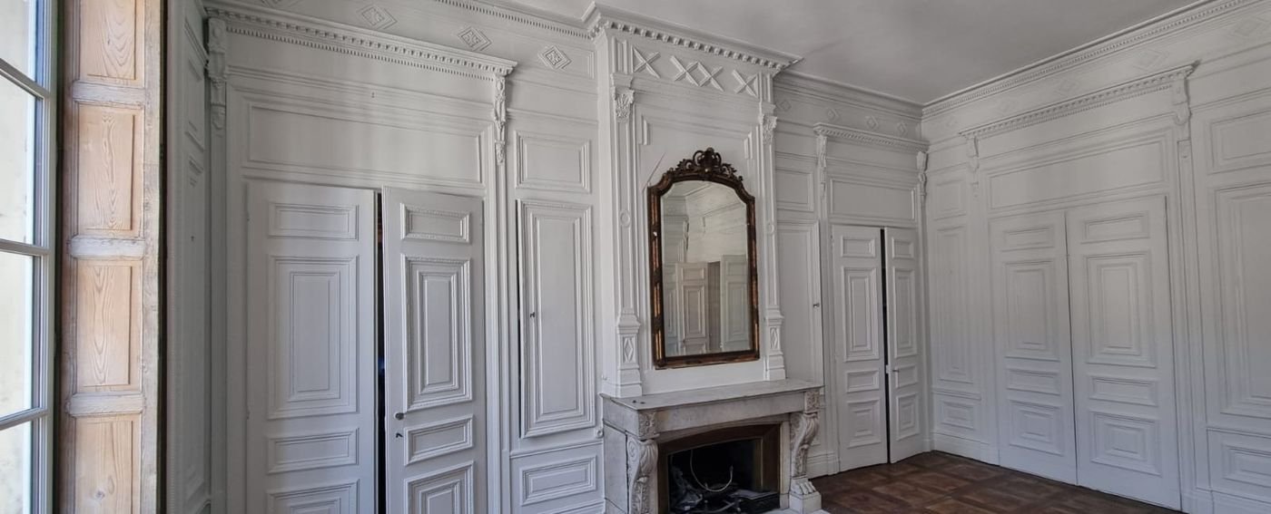 Boiseries et cheminée repeintes en blanc dans un salon ancien